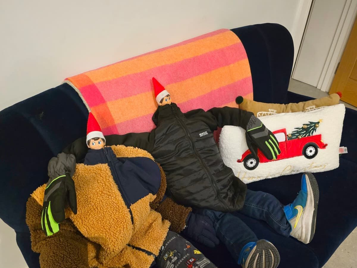 Elf dressed in doll outfit with backpack and lunchbox ready for school adventure.