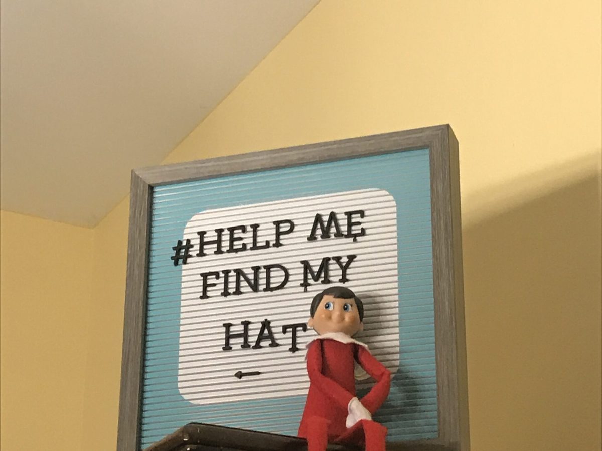 Elf sitting at a table with game rules written on a card in front.