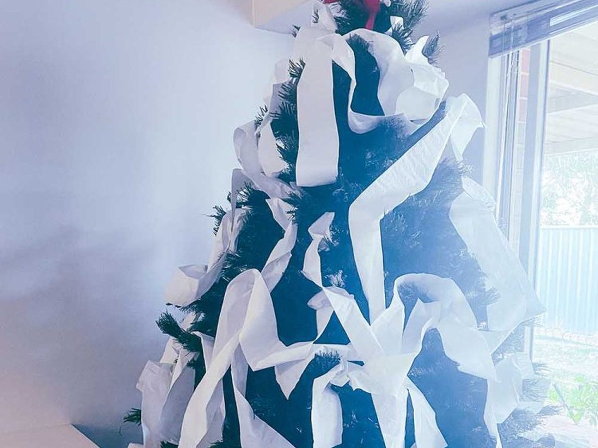 Elf on the shelf sitting on top of toilet papered Christmas tree.