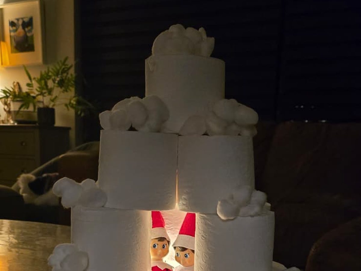 Elf inside toilet paper roll igloo dome with fairy lights glowing inside.