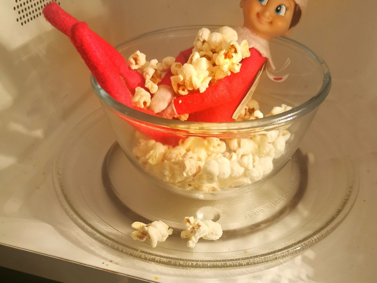 Elf on a couch with a popcorn bowl set up for movie night.