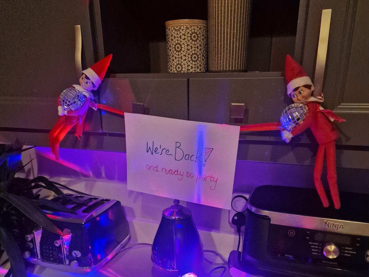 Elf positioned as if dancing with ambient colored lighting creating disco effect.