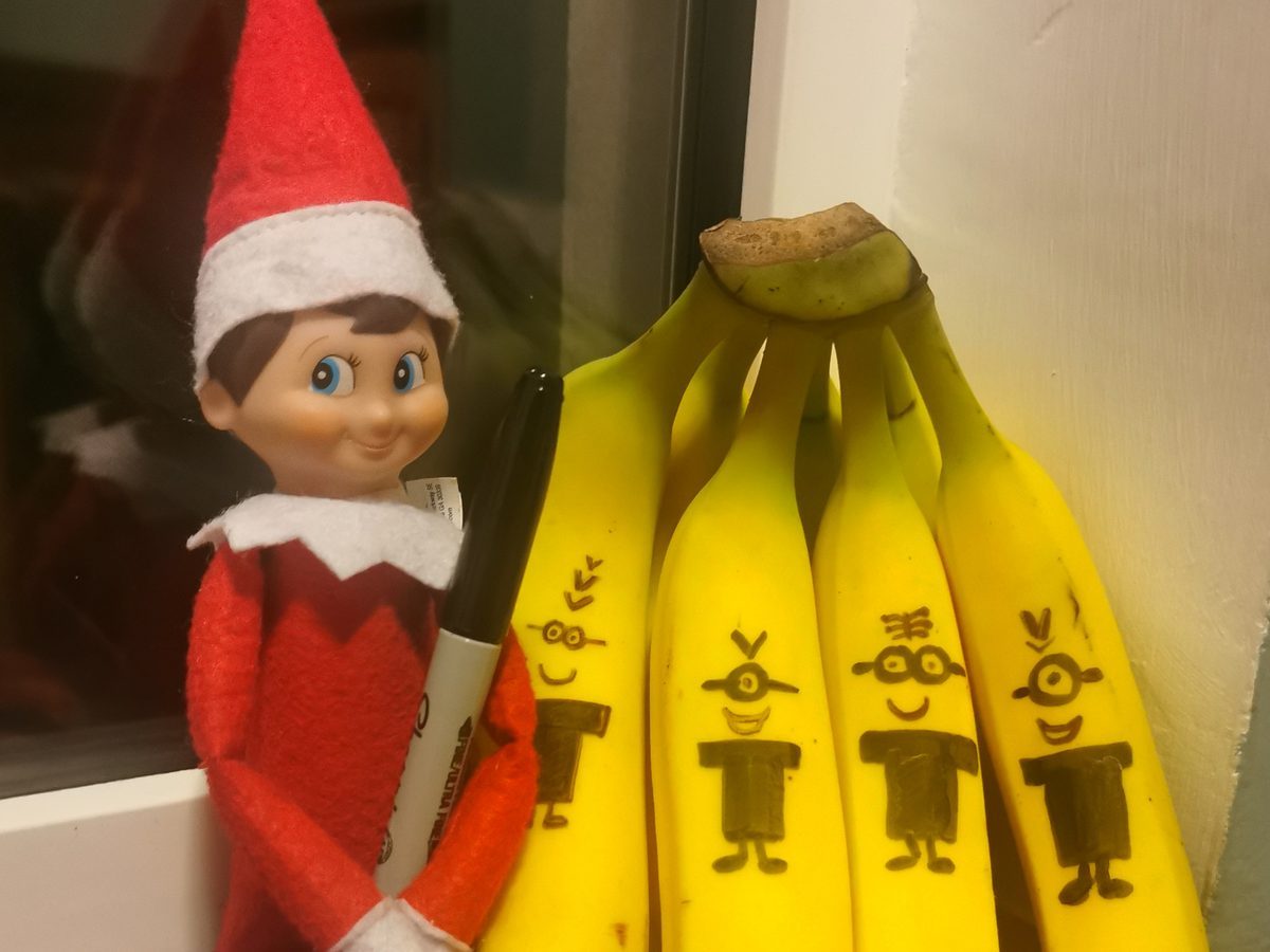 Elf surrounded by bananas decorated as Minion characters with marker.