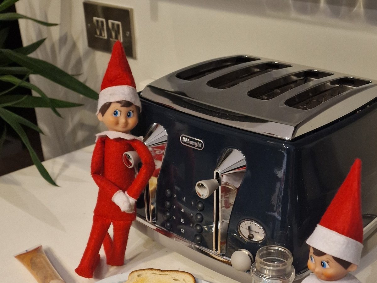 Elf positioned as chef next to colorful rainbow-painted toast breakfast creation.