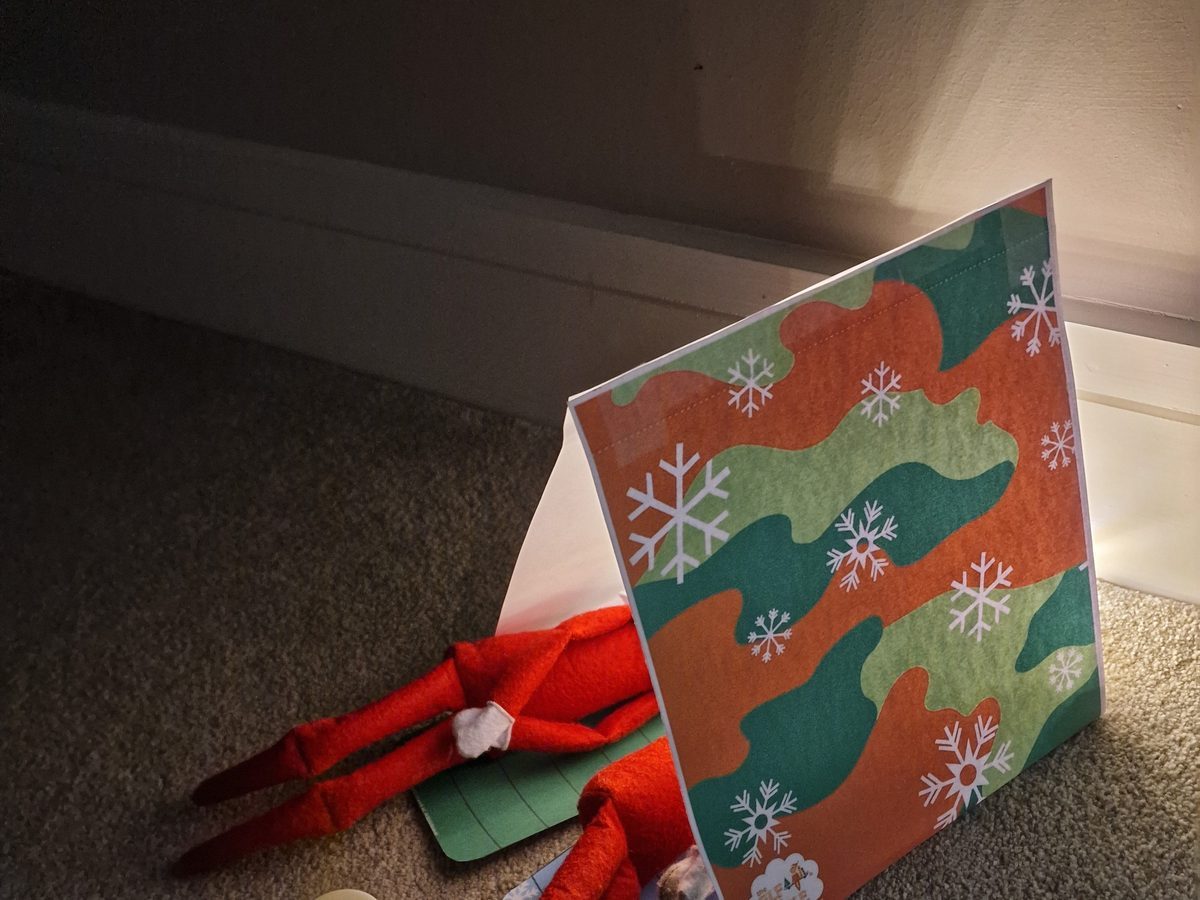 Elf in sleeping bag with red and orange tissue paper campfire and marshmallow.
