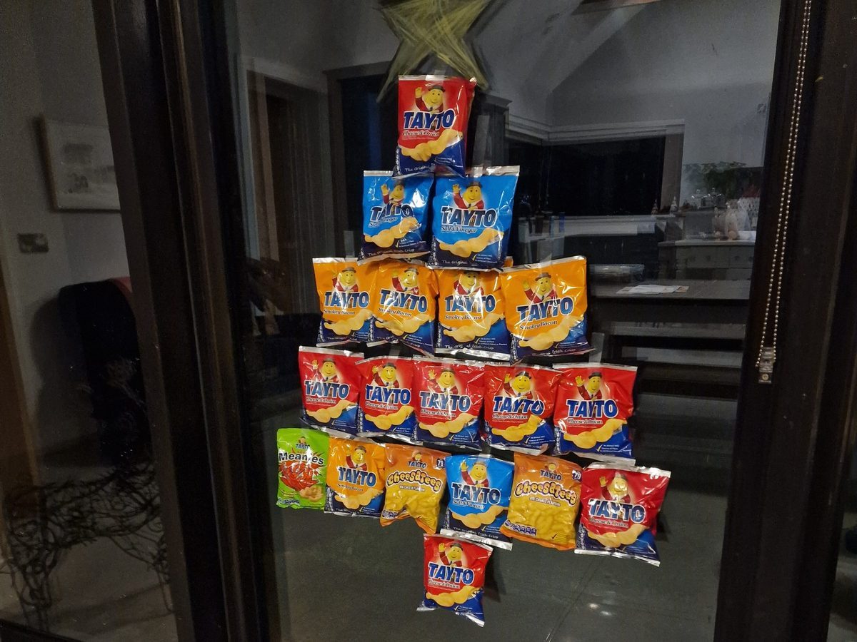 Elf surrounded by stacked snack bags arranged as tree decoration.