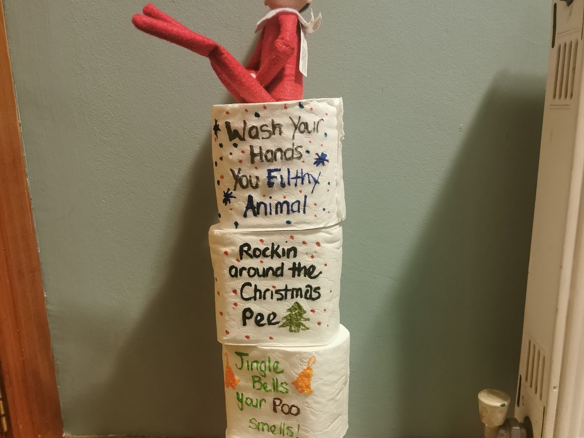 Elf surrounded by toilet paper draped around room as decorations.