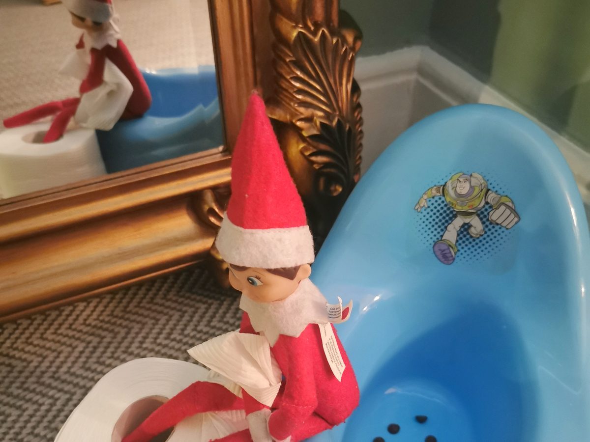 Elf positioned on toy potty chair in bathroom.