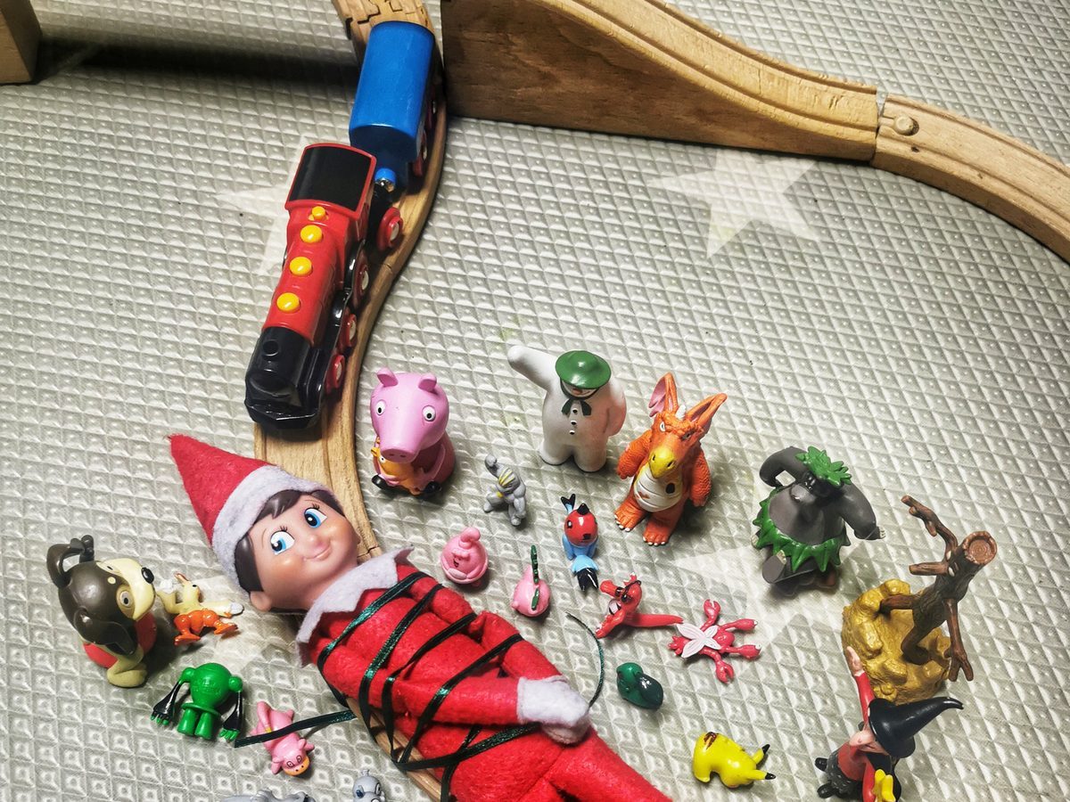 Elf leaping away from toy train on circular track in mid-dodge.